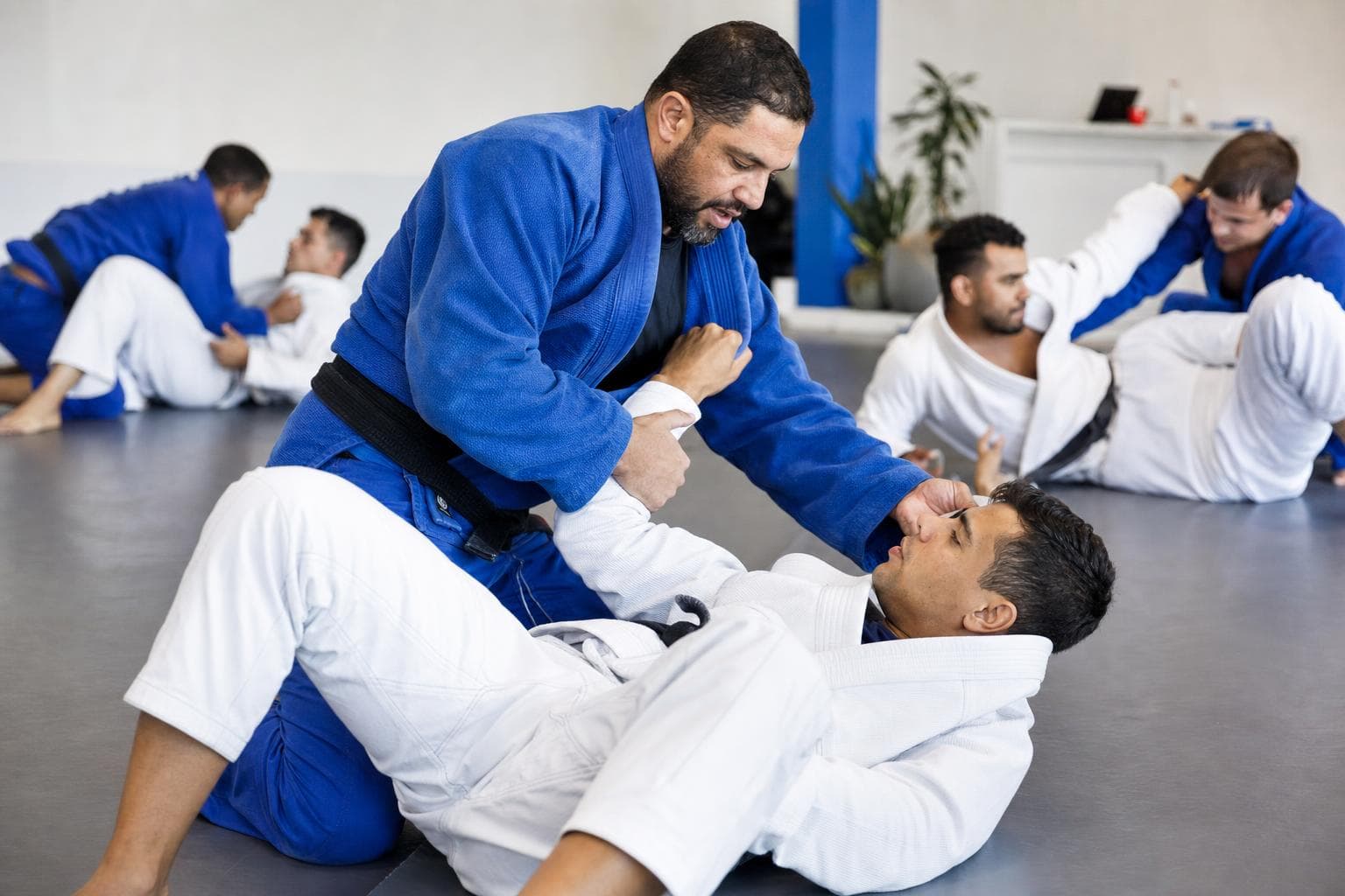 Professor de jiu-jitsu corrigindo a pegada de um aluno no tatame