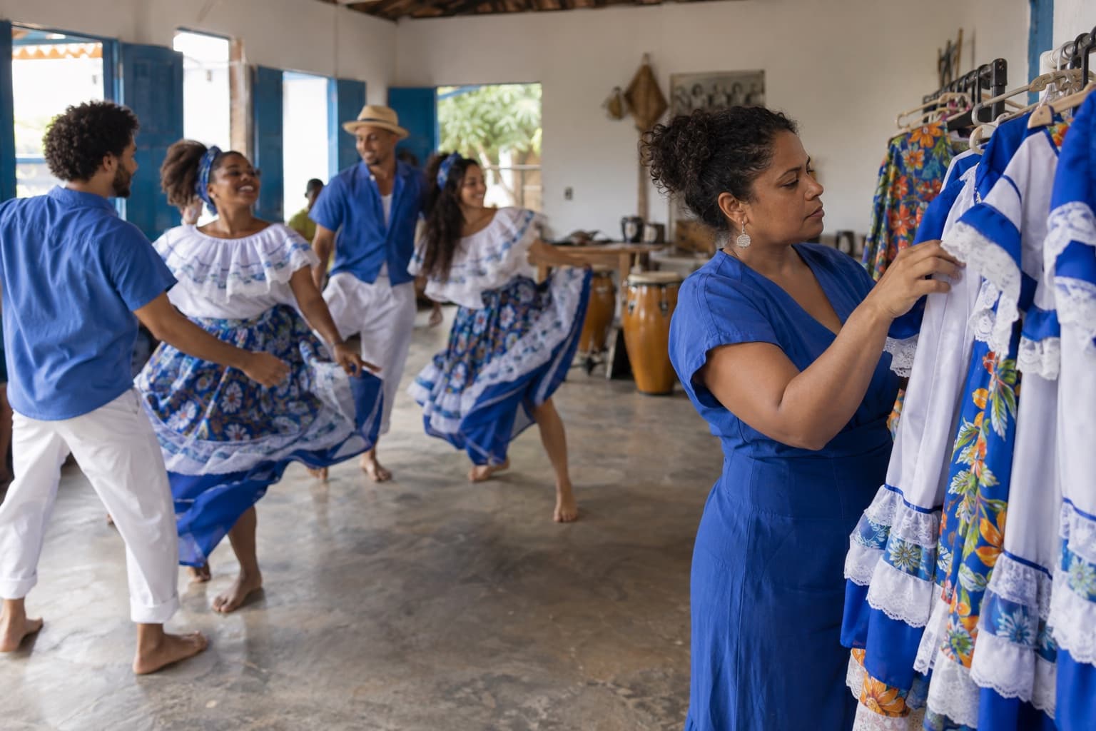 Integrantes de uma associação cultural ensaiando dança folclórica enquanto a coordenadora confere figurinos em uma arara