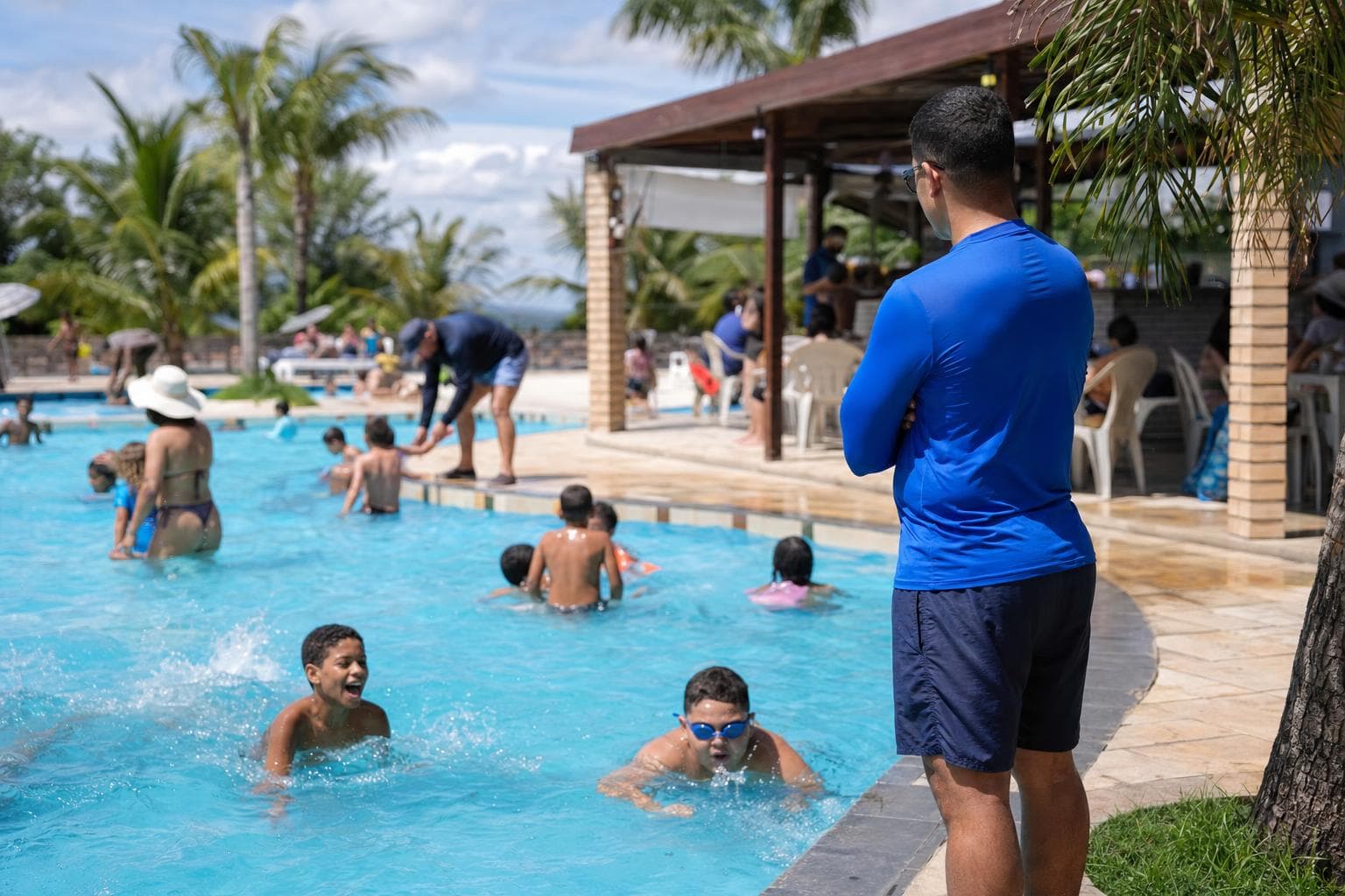 Famílias aproveitando a piscina de um clube recreativo em um dia de sol