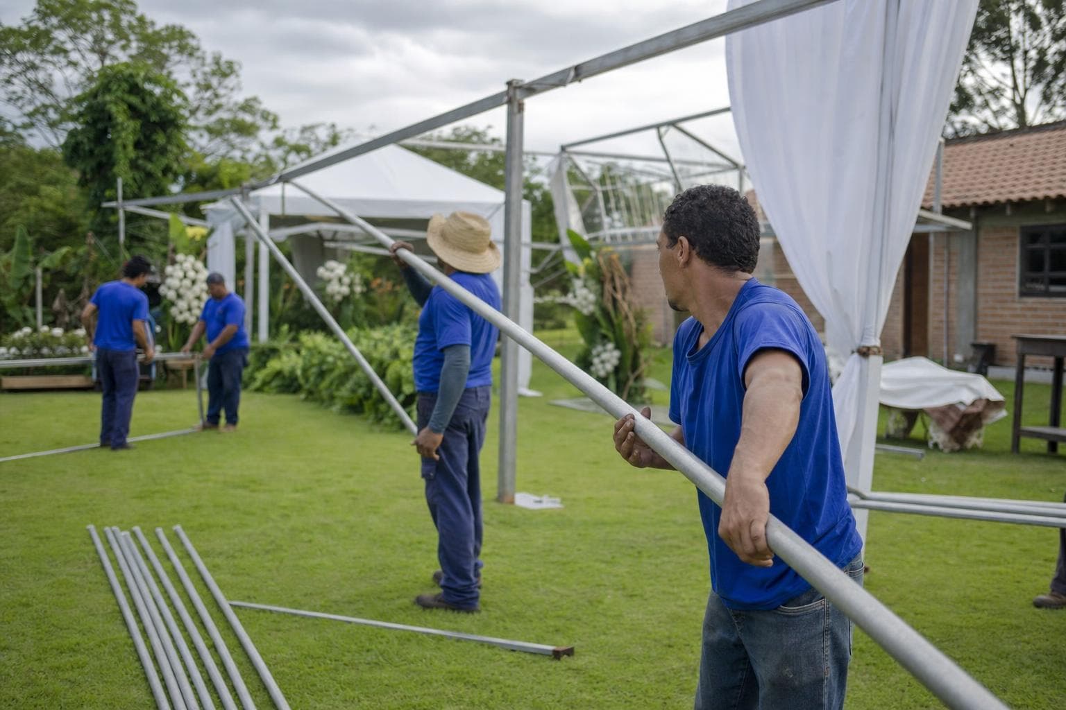 Equipe montando uma tenda branca de estrutura metálica em um gramado