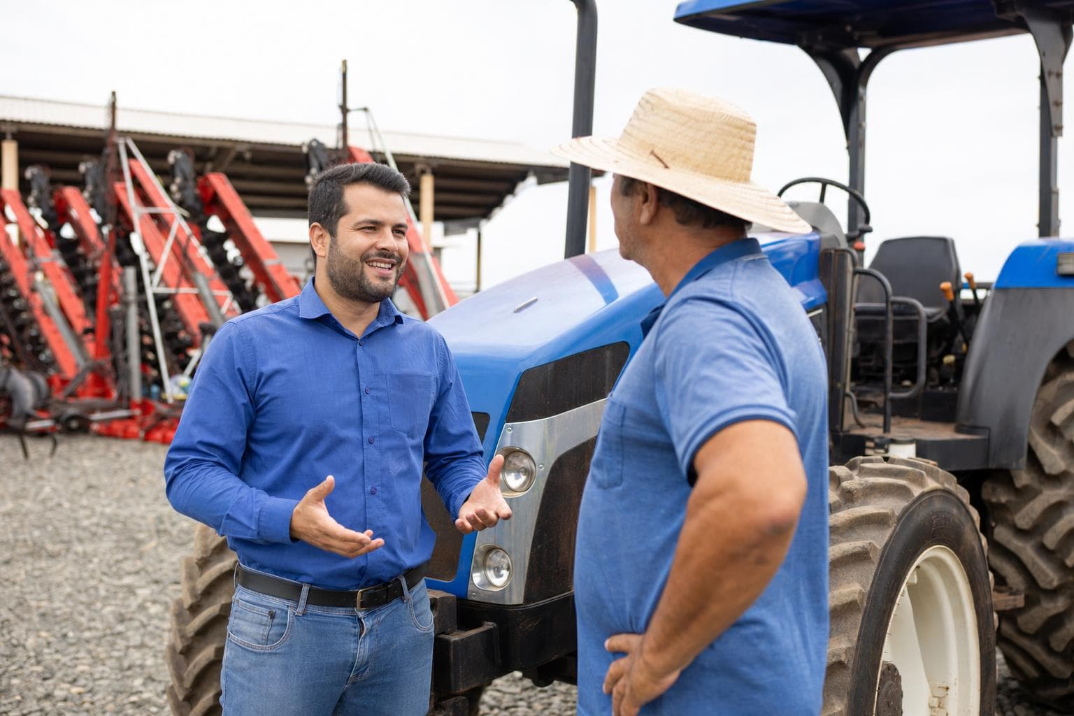 Vendedor apresentando um trator a um produtor rural no pátio de uma revenda de máquinas agrícolas