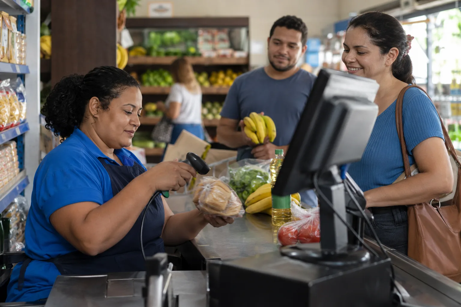 Operadora de caixa registra compras com leitor de código de barras num mercadinho de bairro