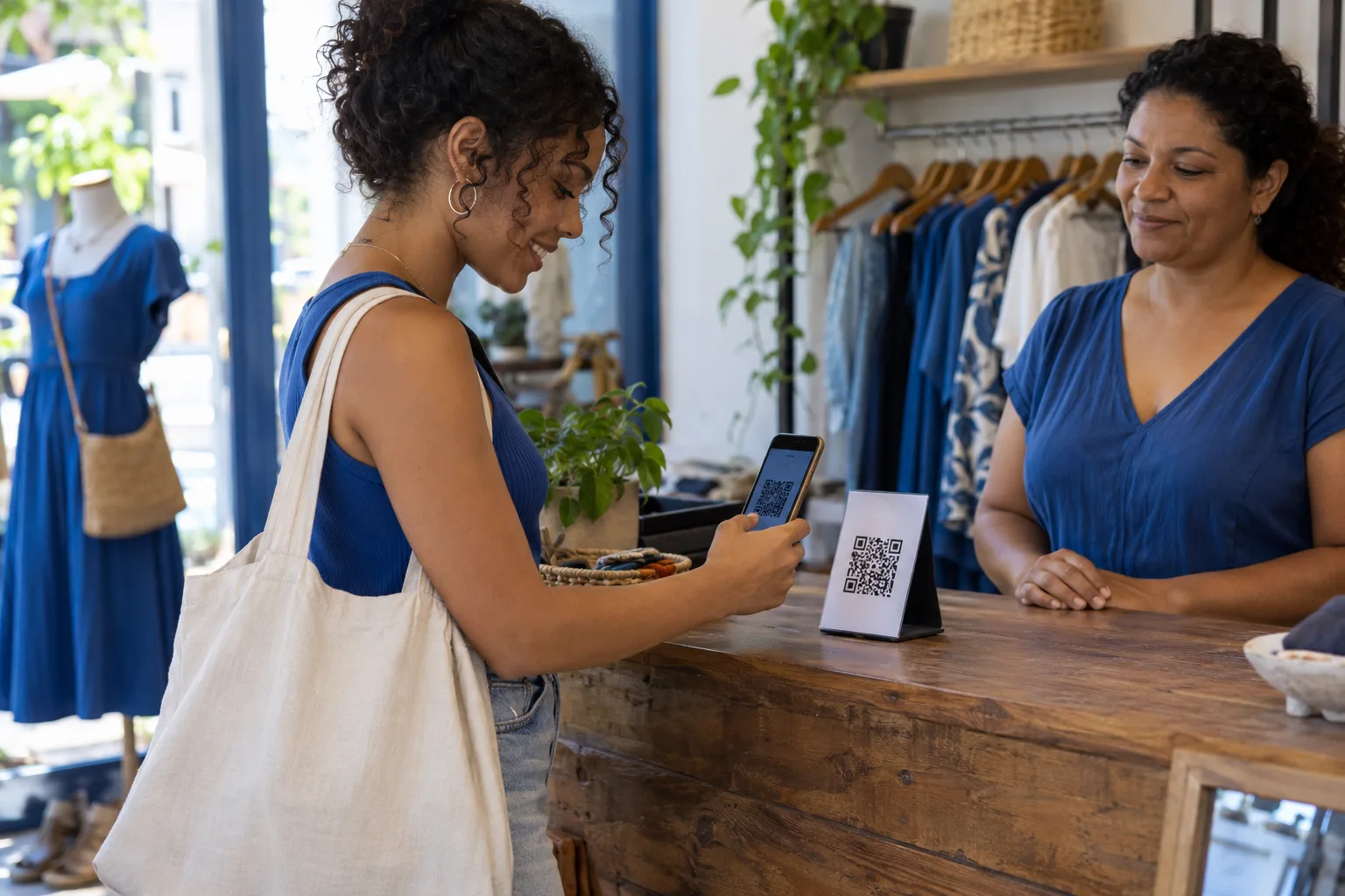 Cliente paga com o celular lendo o QR Code do Pix no balcão de uma loja de roupas