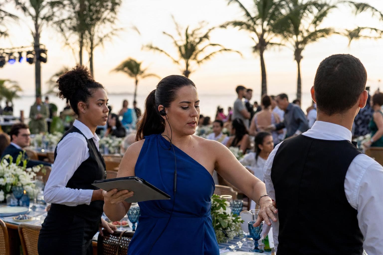 Cerimonialista conferindo o roteiro no tablet enquanto orienta a equipe em uma recepção de casamento
