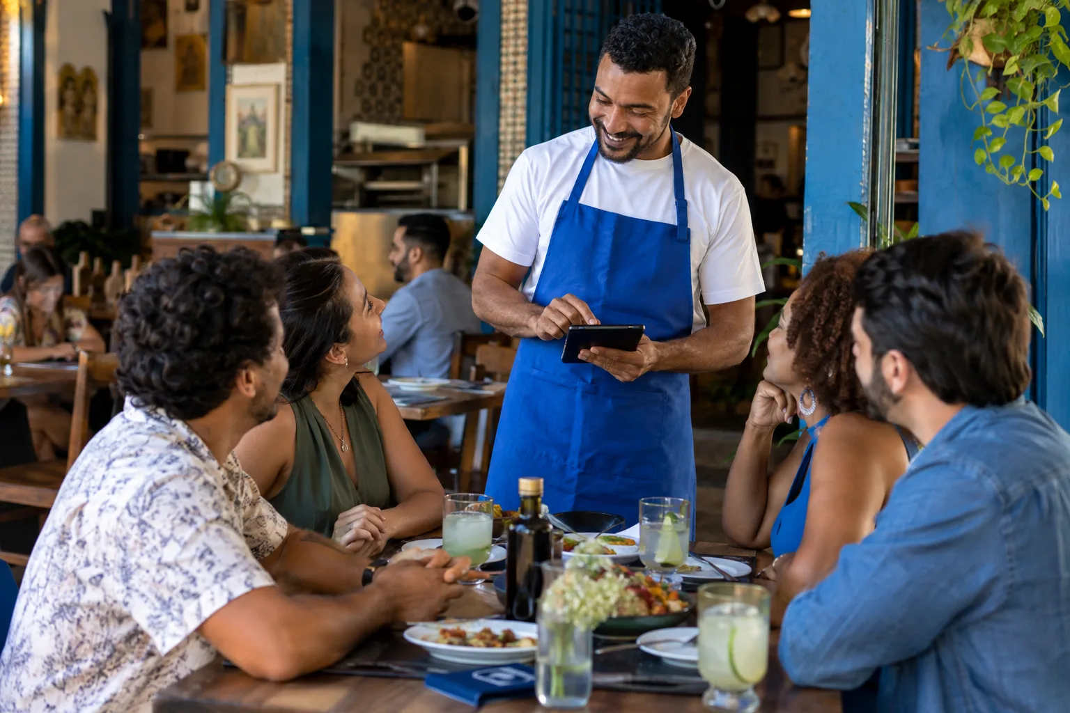 Garçom anota o pedido de uma mesa de amigos em um aparelho portátil no restaurante